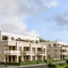 Moderne Wohnanlage mit mehrgeschossigen Gebäuden, Balkonen und Grünflächen unter blauem Himmel mit Wolken